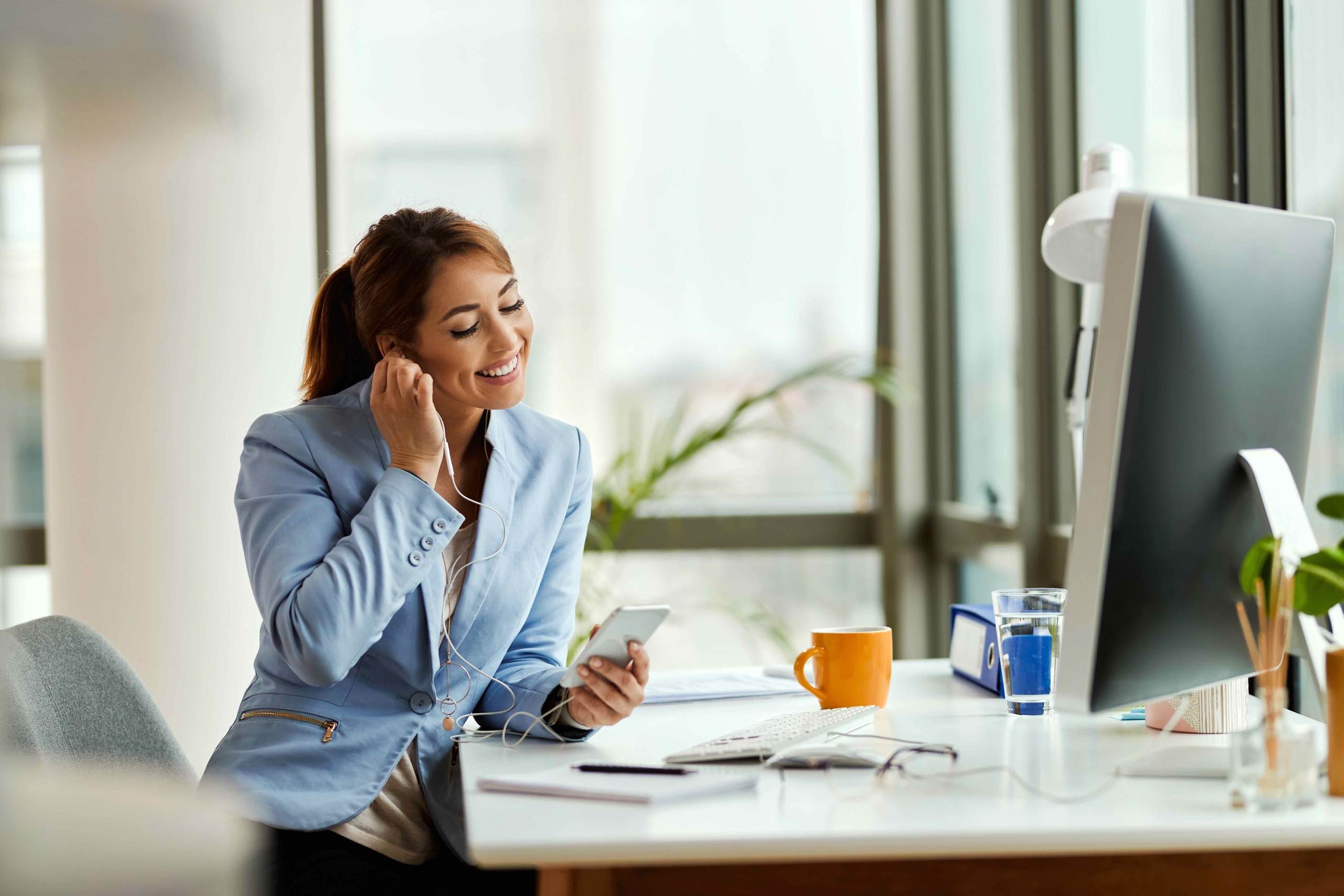 young-businesswoman-relaxing-while-using-mobile-phone-listening-music-earphones-office_1_11zon-scaled_11zon Arconance Rouen 2